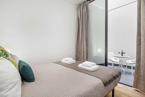 Hotelkamer met een bed, een klein tafeltje met stoelen en uitzicht op het exterieur.