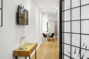 Un intérieur moderne avec une table en bois, un vase en verre et un téléviseur fixé au mur.