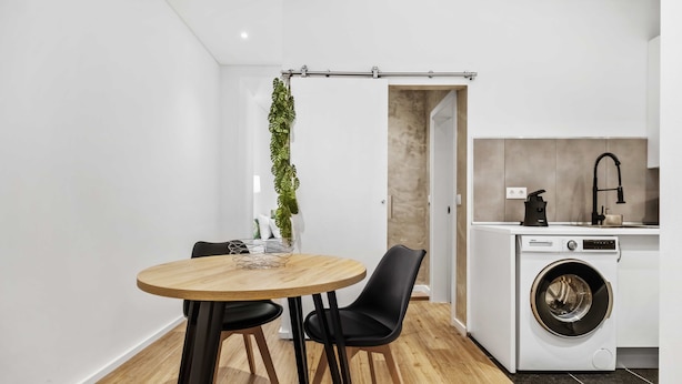A compact kitchen with a washing machine, a dining table with chairs, and a potted plant. - Funchal Tropical - Filodendro by Homie (Funchal)