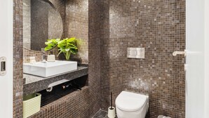 A bathroom with a white sink, a mirror, and a toilet. - Funchal Tropical - Filodendro by Homie (Funchal)
