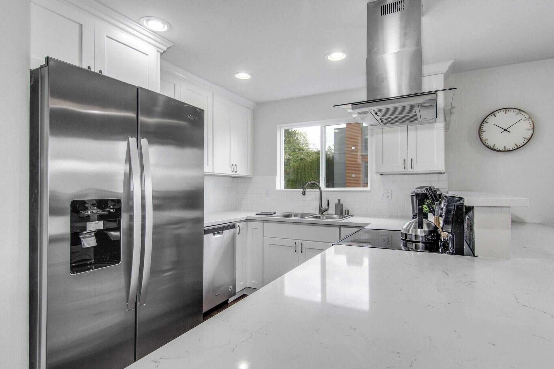 A modern kitchen with stainless steel appliances, white cabinetry, and a large island.