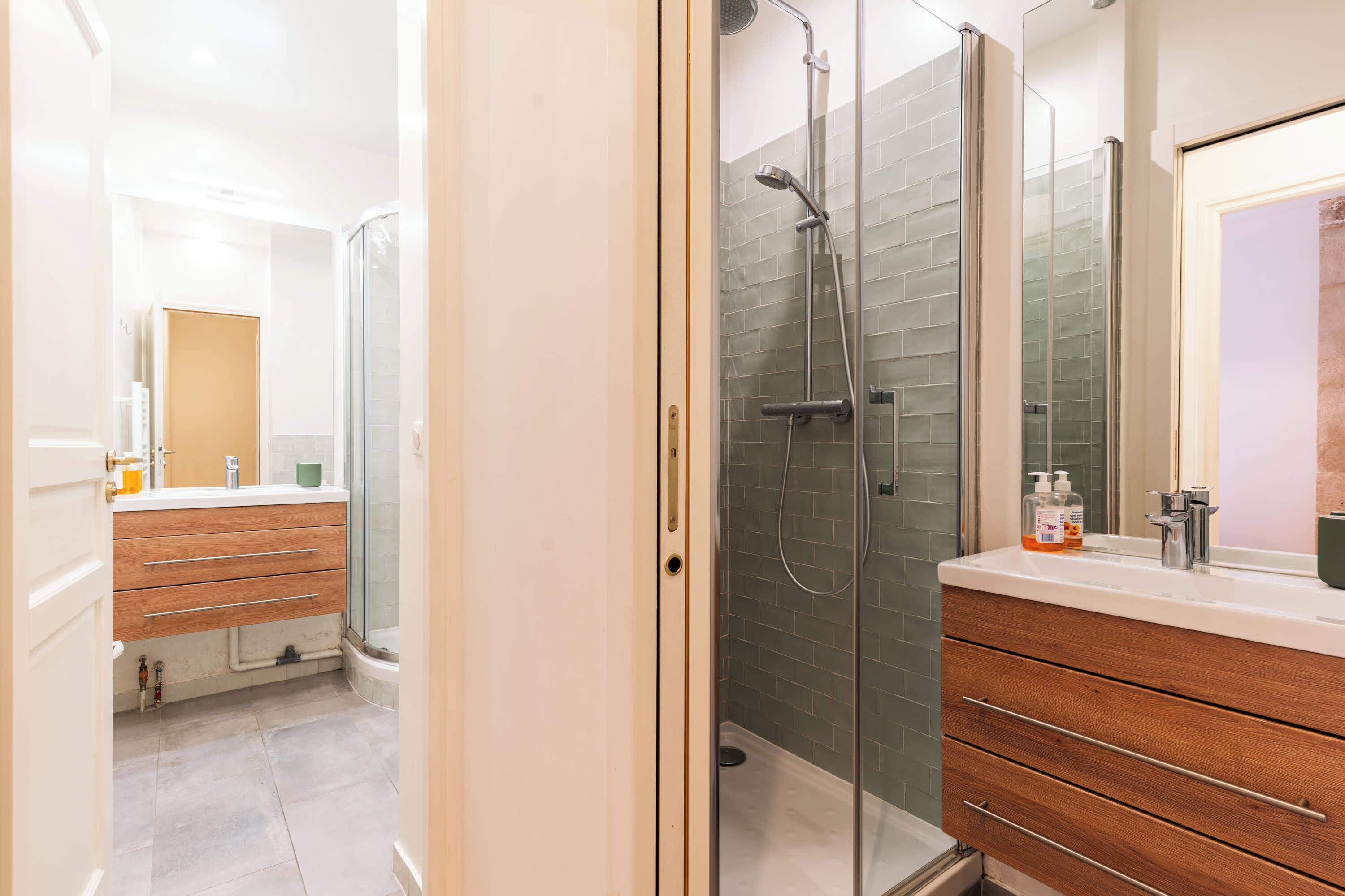 A modern bathroom with a glass-enclosed shower, wooden vanity, and a large mirror.