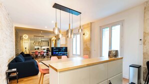 A modern kitchen with a central island, wooden flooring, and pendant lighting.