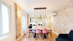 A modern dining area with a stone accent wall, a kitchen in the background, and a blue sofa.