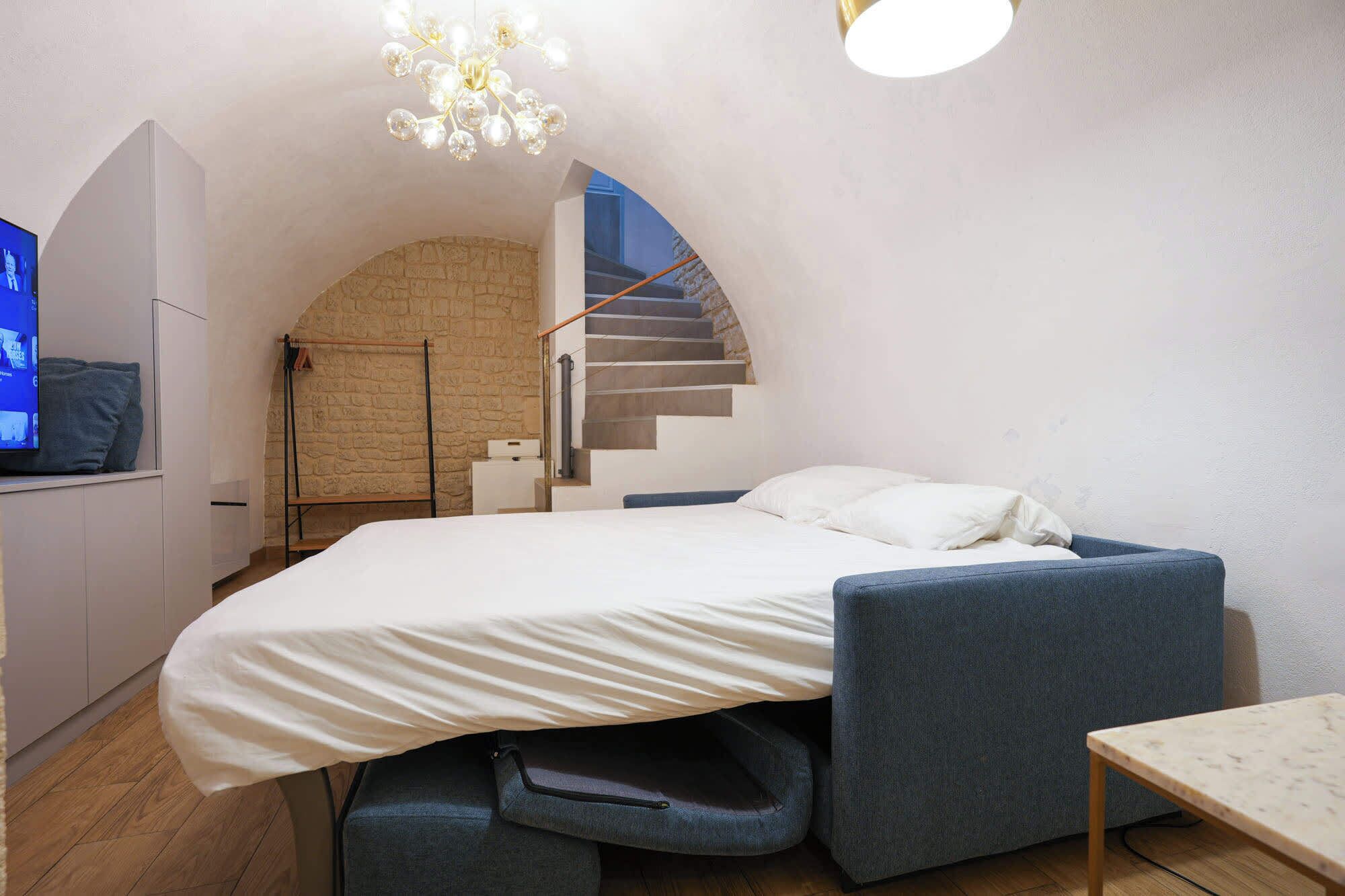 Une chambre à coucher comprenant un lit, un bureau, une chaise, un téléviseur et un escalier.