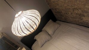 A bedroom with a bed, a textured lamp, and a stone wall. - Loft 2 BR Loft Effeil tower AC by LCC Agency (Paris)