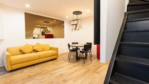 A modern living room with a yellow sofa, a dining table with chairs, and a staircase. - Town House Nation, Bastille, AC by LCC Agency (Paris)