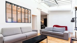 En moderne stue med to sofaer, et sofabord og et ovenlys.