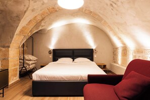 A bedroom with a bed, a red chair, and a stone archway. - Loft 1 BR Marais, Notre Dame AC by LCC Agency (Paris)