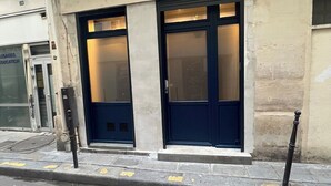 A building with two dark blue doors, a visible window, and a small balcony with a metal railing. - Loft 1 BR Marais, Notre Dame AC by LCC Agency (Paris)