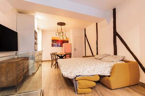 A bedroom with a bed, a wooden cabinet, a TV, a dining table, and a chair. - Loft 1 BR Marais, Notre Dame AC by LCC Agency (Paris)