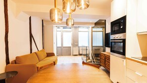 A modern kitchen with built-in appliances, a wooden dining table, and a sofa. - Loft 1 BR Marais, Notre Dame AC by LCC Agency (Paris)