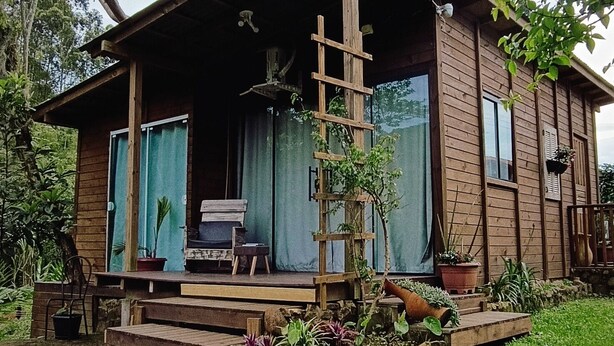 Eine rustikale Holzhütte mit Veranda, Feuerstelle und kleinem Garten.