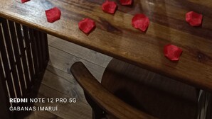Ein gemütliches Zimmer mit Bett, Fernseher und Essbereich, dekoriert mit Rosenblättern und einer Weinflasche.