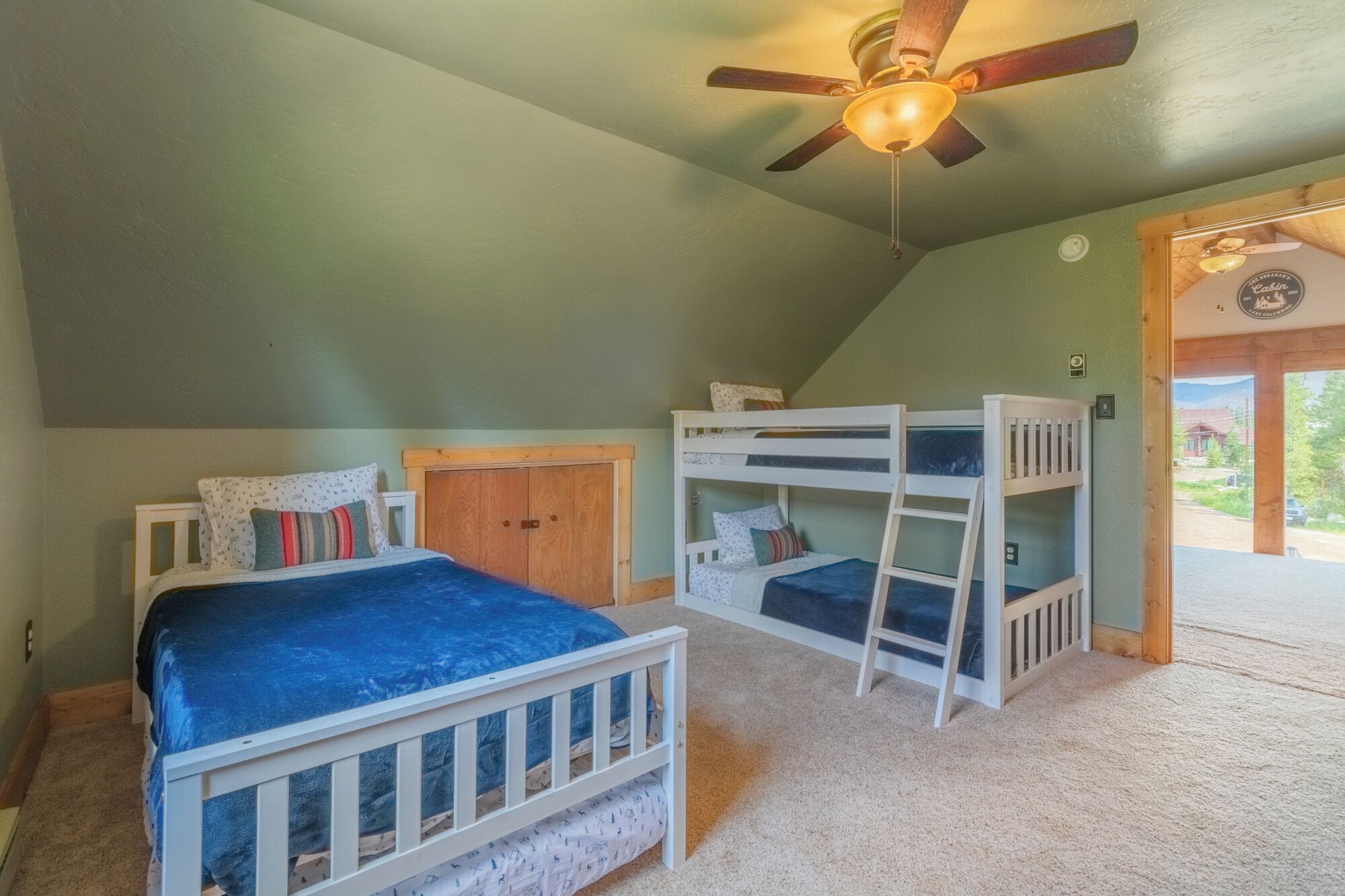 Un dormitorio con literas, ventilador de techo y puerta que da al exterior.