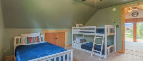 Un dormitorio con literas, ventilador de techo y puerta que da al exterior.