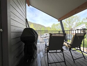 A covered porch with a grill and two chairs.