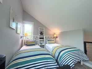 A bedroom with two beds, a window, and a shelf with items. - Elk View Basecamp - wildlife and convenience! (Telluride)