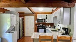 A compact kitchen with wooden cabinets, a built-in microwave, and a stainless steel refrigerator.