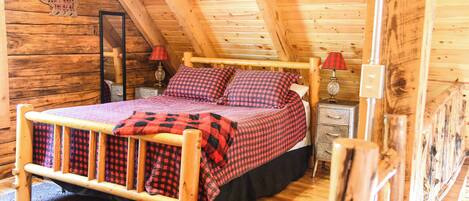 Una camera da letto accogliente in una baita di legno, con un letto, due comodini e un tavolino di fianco al letto.