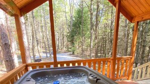 A hot tub under a wooden deck with a forest view. - Happy Bear Log Cabin near Cook Forest State Park (Leeper)