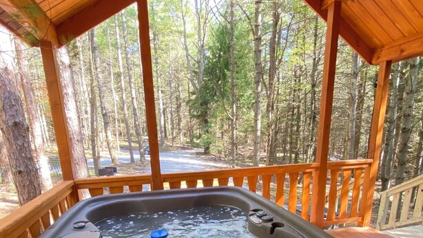A hot tub under a wooden deck with a forest view.
