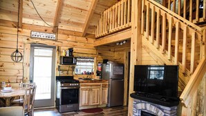 Ein Blockhaus-Interieur mit Küche, Essbereich und Kamin.