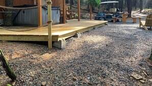 A rustic cabin with a wooden deck, a hot tub, and a golf cart. - The Hideaway near Cook Forest State Park (Leeper)