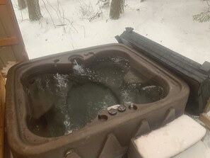 A hot tub with water flowing, surrounded by snow.