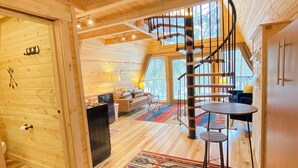 A wooden interior with a spiral staircase, a dining area, and a patterned rug. - The Treehouse near Cook Forest State Park (Leeper)