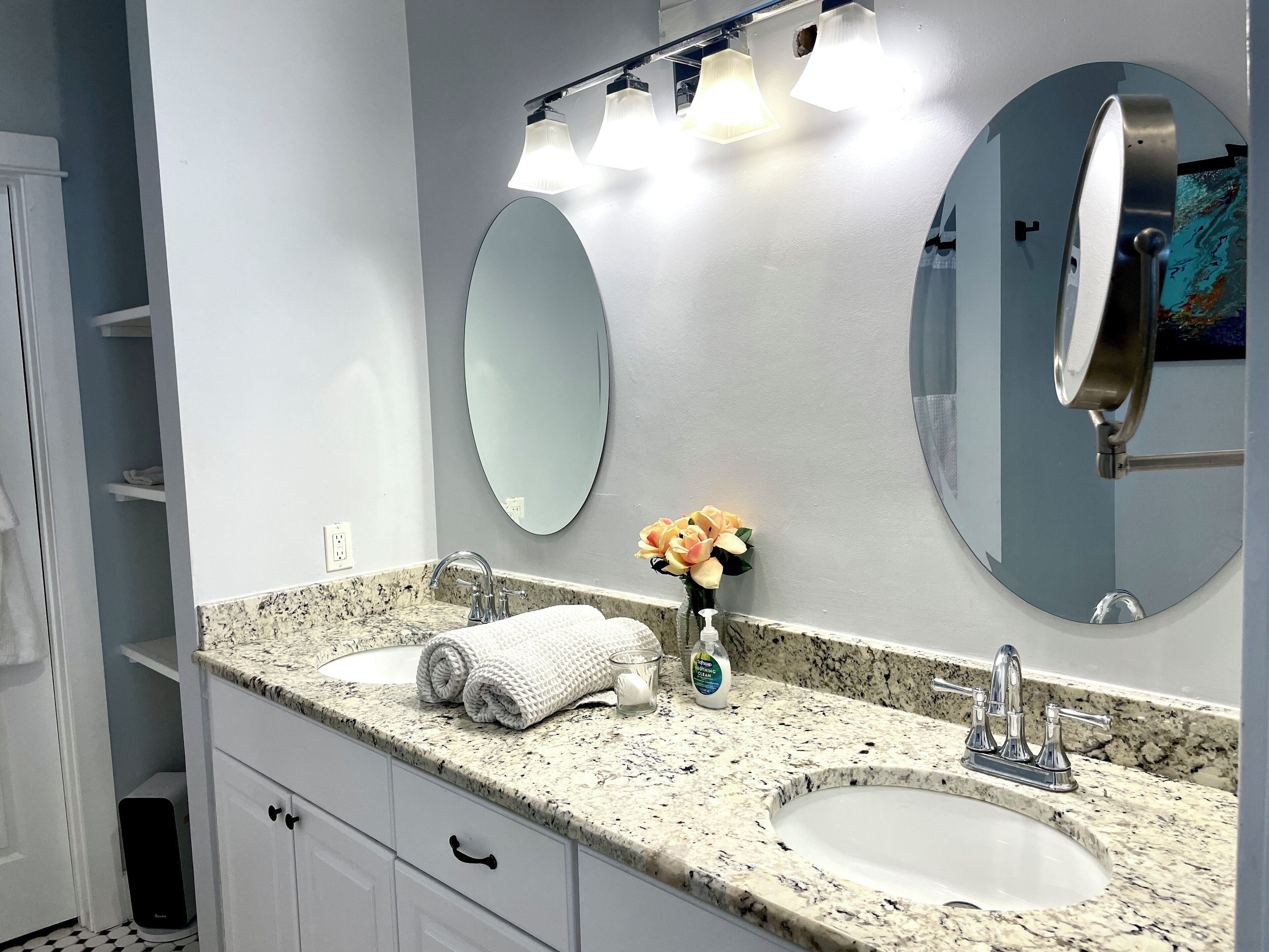A bathroom with two sinks, a large mirror, and a towel rack.