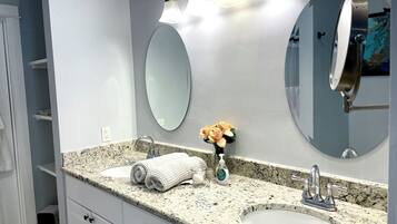 A bathroom with two sinks, a large mirror, and a towel rack.