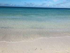 Une plage avec une eau claire et peu profonde et un rivage sablonneux.