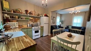 A compact kitchen with a wooden island, a dining table with chairs, and a sofa in the adjacent living area.