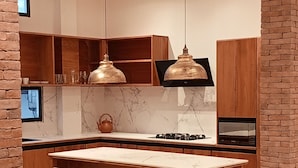 A modern kitchen with a central island, two bar stools, pendant lighting, and built-in appliances. - Galapagos Coliving Ecuador Casa Tuna (Puerto Ayora)