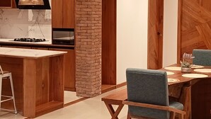 A modern kitchen with a central island, wooden cabinets, and a brick accent wall. - Galapagos Coliving Ecuador Casa Tuna (Puerto Ayora)