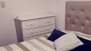 A bed with striped bedding, a rolled towel, and a headboard with buttons. - Buenos Aires de Ezeiza Resort Vacacional - Departamento N°1 (La Unión)