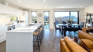 Een moderne keuken met een centraal eiland, barkrukken en een eethoek met tafel en stoelen.