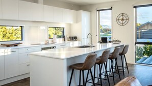 Een moderne keuken met een groot eiland, barstoelen en uitzicht op de omgeving.