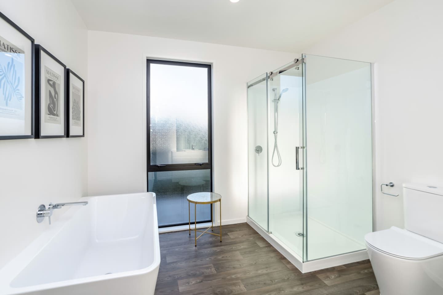 A modern bathroom with a glass-enclosed shower, a freestanding bathtub, and a toilet.