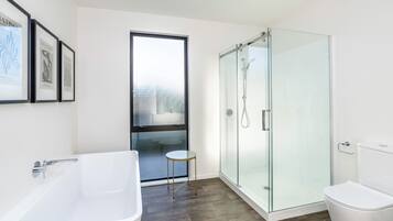 A modern bathroom with a glass-enclosed shower, a freestanding bathtub, and a toilet.