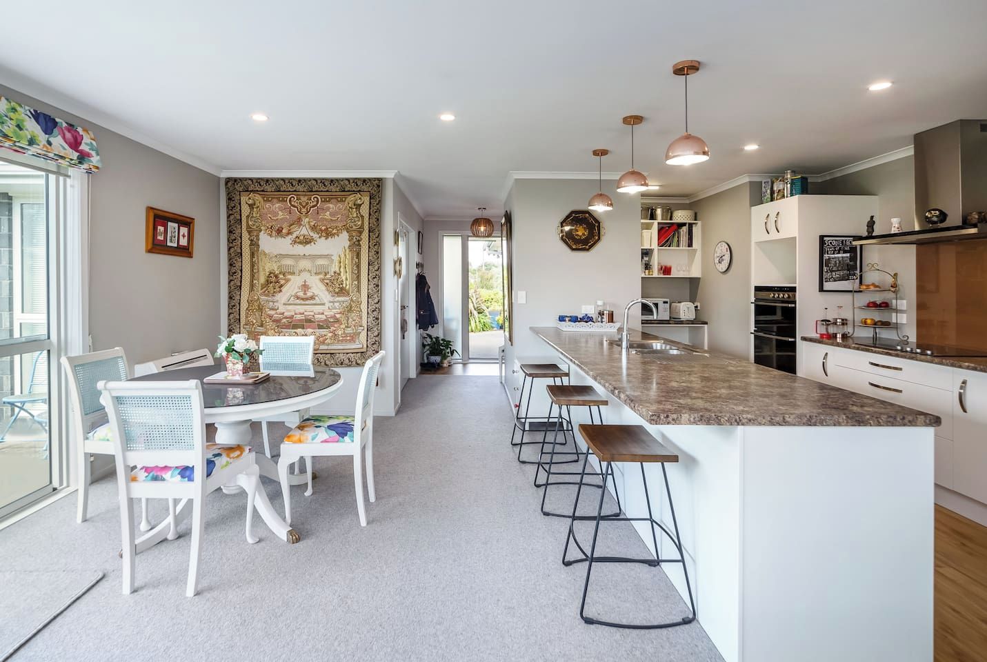 A modern kitchen with a central island, bar stools, and pendant lighting.