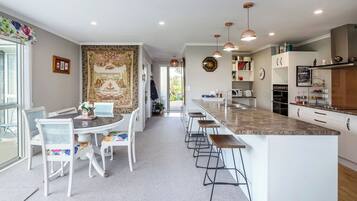 A modern kitchen with a central island, bar stools, and pendant lighting.