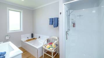 A bathroom with a bathtub, a shower, a toilet, and a window.