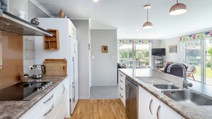A modern kitchen with white cabinets, a wooden countertop, and a built-in oven. There is a window with a view of the outdoors. - Michaelia House, Greytown (Greytown)