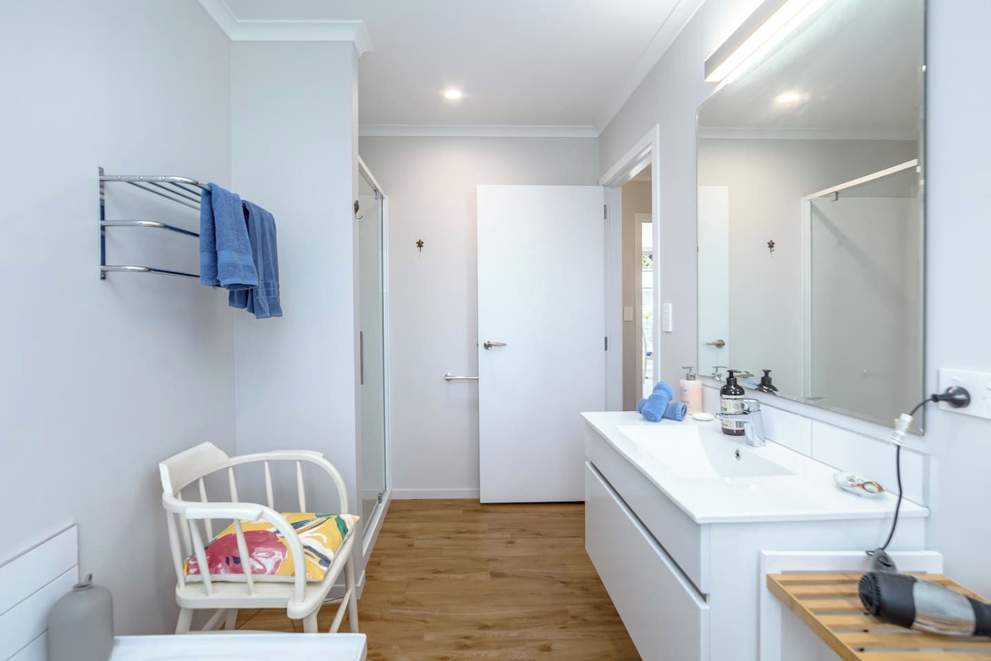 A modern bathroom with a white sink, mirror, and towel rack.