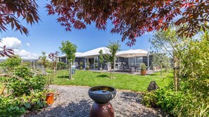 A modern building with a well-maintained garden, outdoor seating, and a clear view of the sky. - Michaelia House, Greytown (Greytown)