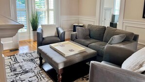 A living room with a grey sofa, a matching ottoman, a white coffee table, and a potted plant. - Stylish home next to train to Boston, near Salem (Wakefield)