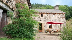 Una casa de piedra con techo de tejas, puerta de madera y un paraguas rojo.
