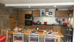 A modern kitchen with wooden cabinets, a central island, and a dining area with chairs. - Gîte La Parro - MALBOUZON (MALBOUZON)